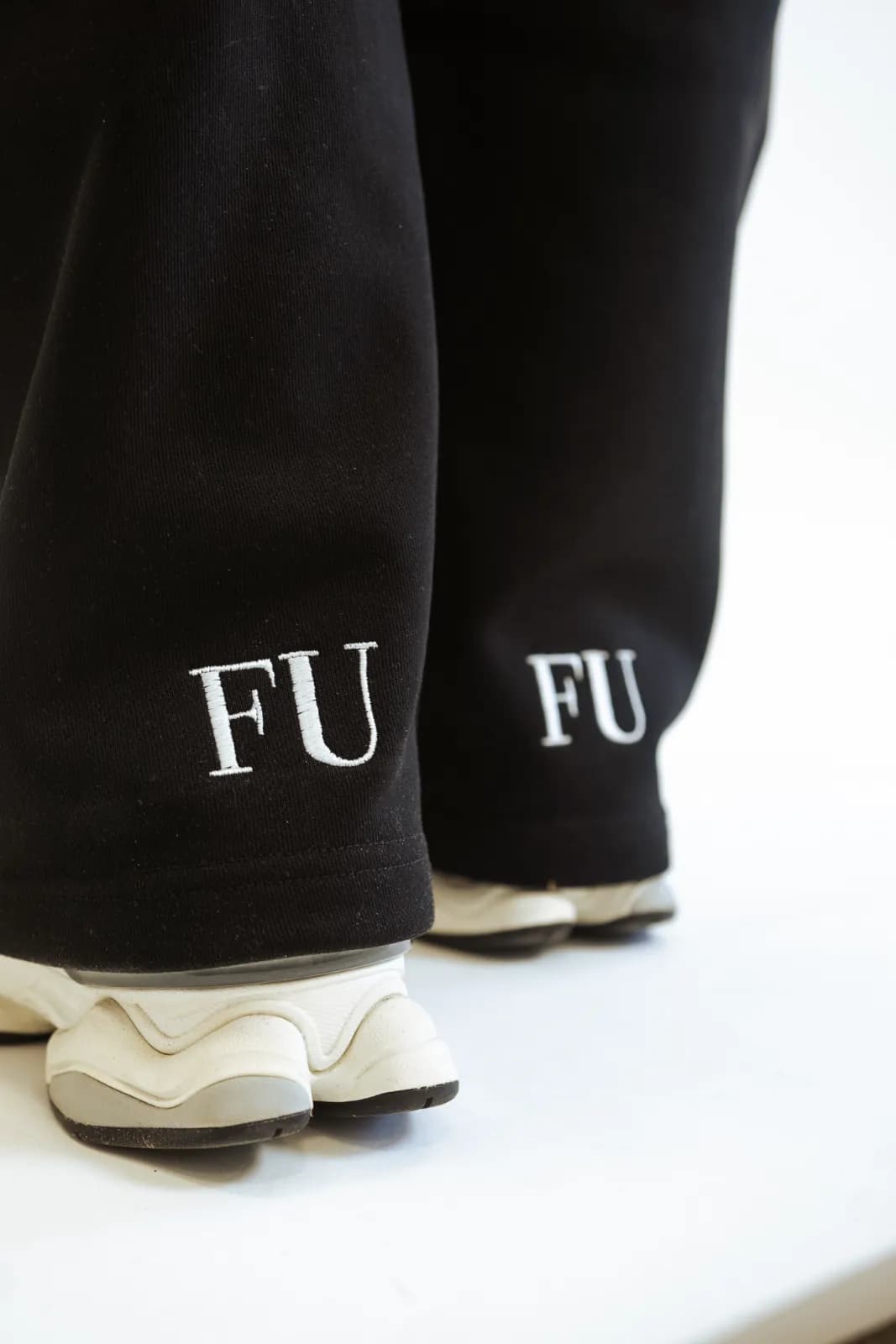Embroidered FU monogram on the back hem of the black wide-leg sweatpants